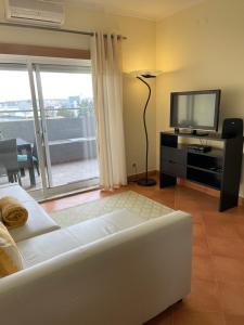 sala de estar con sofá blanco y TV de pantalla plana en Condominio do Mar, en Lagos