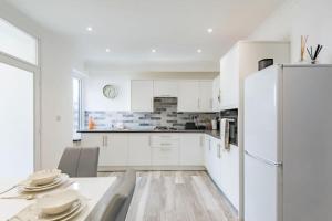 a white kitchen with a table and a refrigerator at Stone's Throw in Deal