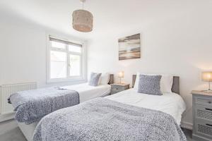 two beds in a room with white walls and a window at Stone's Throw in Deal