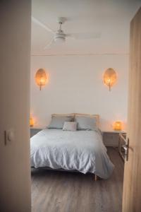 a bedroom with a bed with two lights on the wall at Villa romantique, Rêve d'ailleurs, saint leu, la Réunion in Saint-Leu
