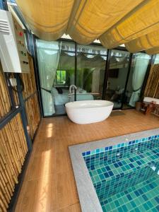 素叻Phetra pool villas的浴室配有浴缸和水槽。