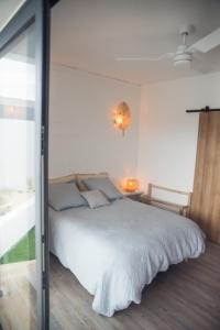 1 dormitorio con cama blanca y ventana en Villa romantique, Rêve d'ailleurs, saint leu, la Réunion, en Saint-Leu
