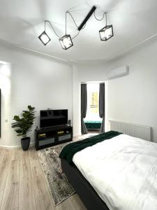 a white bedroom with a bed and a television at Green Spot - Premium Studio - Sanador Victoriei in Bucharest
