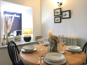 a wooden table with plates and glasses and a candle at Mill Cottage Modern Boutique Cosy Home in Lake District Village near Scafell in Gosforth
