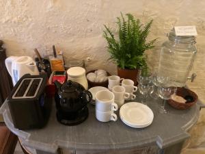 a table with cups and mugs and a tea kettle at Peaceful Farmhouse stay with cozy Yard in Għarb