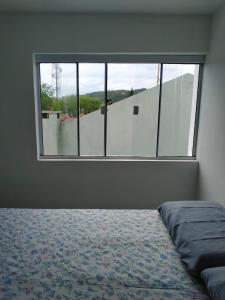 1 dormitorio con cama y ventana grande en Loft/APTO em Praia da Pinheira, en Pinheira
