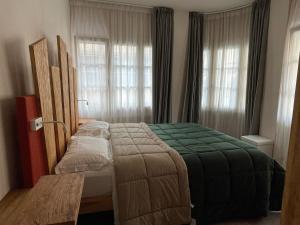 a bedroom with a green bed in front of windows at B&B VIA ROMA 25 in Arezzo