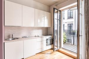 a kitchen with white cabinets and a large window at Subačiaus studio in OLD TOWN in Vilnius