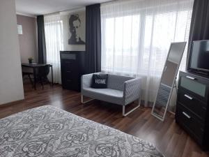 a bedroom with a chair and a television and a table at Vienibas apartment in Daugavpils