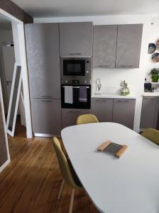 een keuken met een witte tafel met stoelen en een magnetron bij La Citadine maison de ville avec garage in Bagnères-de-Bigorre