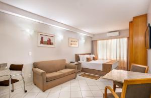 um quarto de hotel com uma cama, um sofá e uma mesa em Plaza Inn American Loft em São Paulo