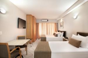 a hotel room with two beds and a table at Plaza Inn American Loft in Sao Paulo