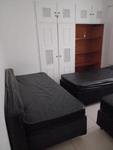 2 Betten in einem Zimmer mit weißen Schränken und schwarzen Matratzen in der Unterkunft Apartamento em Praia Grande - Frente ao Mar in Praia Grande
