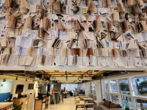 una pared de libros colgando del techo de una biblioteca en ibis Styles Poços de Caldas en Poços de Caldas