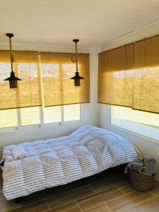 a bedroom with a bed and windows with blinds at El fortín del Rubio in Cabo Polonio