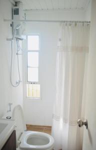 a bathroom with a white shower curtain and a toilet at El fortín del Rubio in Cabo Polonio