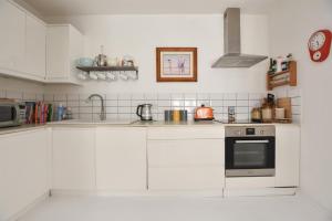 eine Küche mit weißen Schränken und einem Herd mit Backofen in der Unterkunft Stunning 2 bed with Sea View in Hastings Old Town in Hastings + 20 Fotos