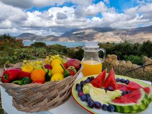 a plate of fruit and a basket of orange juice at Forestata Village in Lixouri