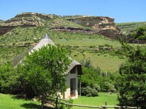 a small house with a thatched roof in a field at Mafube Mountain Retreat in Fouriesburg