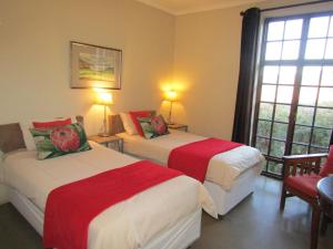 a hotel room with two beds with red and white sheets at Mafube Mountain Retreat in Fouriesburg