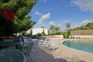 a patio with tables and chairs and a swimming pool at La Pandilla Ibiza in Sant Francesc de s'Estany