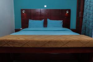 une chambre avec un grand lit à tête de lit en bois dans l'établissement LIEBE HOTEL, à Yaoundé