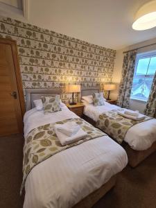 a hotel room with two beds and a window at Royal Oak Braithwaite in Keswick +4 photos