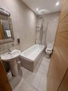a bathroom with a tub and a sink and a toilet at Royal Oak Braithwaite in Keswick