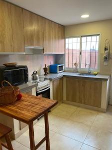 una cocina con armarios de madera y una mesa. en Casa Los Perales en San Salvador de Jujuy