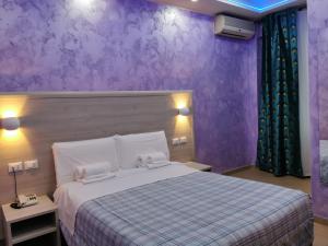 um quarto com uma cama grande e paredes roxas em Hotel Orchidea em Turim