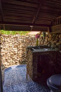 Baño de piedra con lavabo y pared de piedra en Casa Balae, en Nuquí