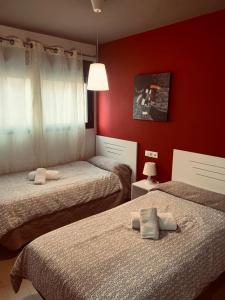 two beds in a room with red walls at Apartamentos 16:9 Suites Almería in Almería