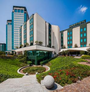 un edificio de hotel con un jardín delante de él en Cosmo Hotel Torri, en Vimercate