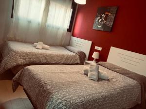 dwa łóżka w pokoju z czerwonymi ścianami w obiekcie Apartamentos 16:9 Suites Almería w mieście Almería +37 zdjęć