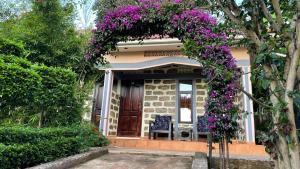 een huis met een krans van paarse bloemen op de deur bij Home of Friends in Kapchorwa
