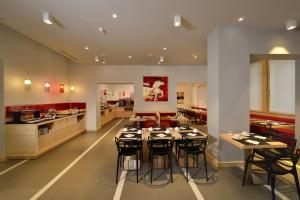 a dining room with tables and chairs and a kitchen at Hotel Carlton in Ferrara