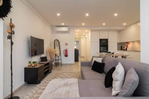 een woonkamer met een grijze bank en een keuken bij Stylish Apartment W/ River View by LovelyStay in Oeiras