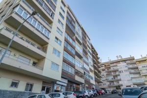 un condominio alto con auto parcheggiate in un parcheggio di Stylish Apartment W/ River View by LovelyStay a Oeiras
