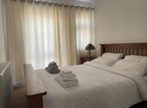 a bedroom with a white bed with towels on it at Newly built modern flat at London Gants Hill Station near Ilford in Wanstead