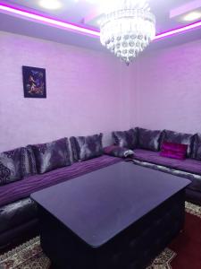 a living room with a purple couch and a chandelier at APPARTEMENT AMIRA iFRANE in Ifrane