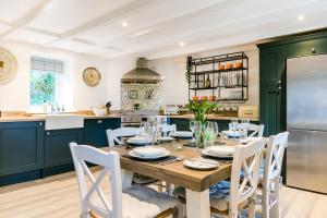 a kitchen with a wooden table and white chairs at Courtyard Cottage - within the Helland Barton Farm collection in Delabole