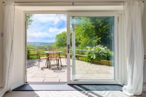 an open door to a patio with a table at Goose Cottage - within the Helland Barton Farm collection in Delabole