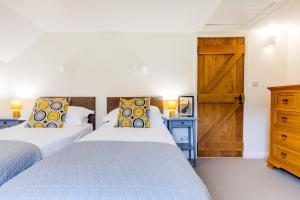 a bedroom with two beds and a wooden door at Goose Cottage - within the Helland Barton Farm collection in Delabole