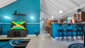 ein Wohnzimmer mit blauen Wänden und eine Bar mit Hockern in der Unterkunft Casa Maurice Ocho Rios Villa in Ocho Rios