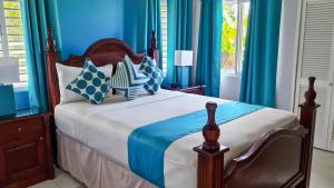 Schlafzimmer mit einem Bett mit blauen Wänden und blauen Vorhängen in der Unterkunft Casa Maurice Ocho Rios Villa in Ocho Rios