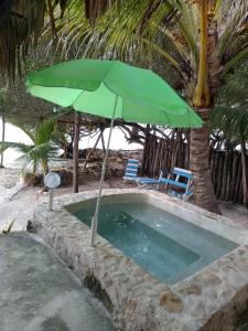 zielony parasol siedzący obok basenu w obiekcie Casa GAMA-Playa ORILLA DEL MAR, Beach and Town w mieście Boxol