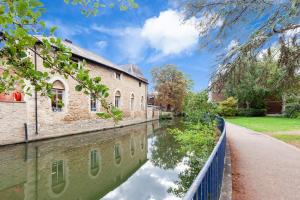 a canal in front of a building with a reflection in the water at La casetta d’Àneu, Oxford Castle in Oxford