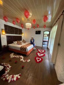 una persona seduta su un letto in una stanza con decorazioni rosse di Aldea Real Eco Friendly a Baños