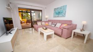 ein Wohnzimmer mit einem rosa Sofa und Tischen in der Unterkunft Coto Real Duquesa Manilva in Manilva