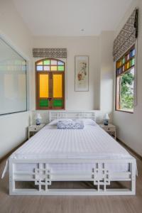 a white bedroom with a large bed and two windows at O'nya Phuket Hotel - SHA Extra Plus in Phuket